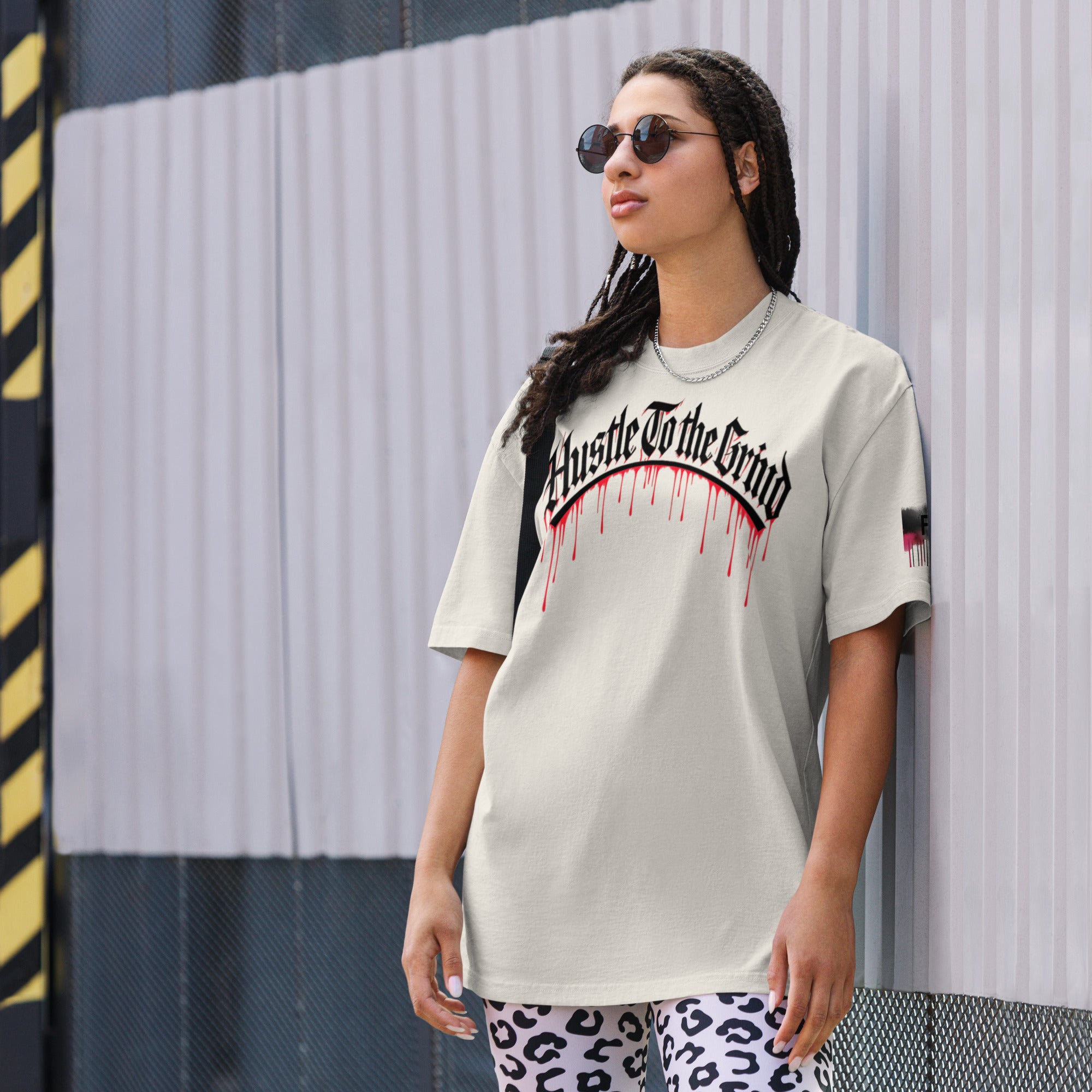 Oversized unisex “Hustle To the Grind” T-shirt in faded white, showcasing urban graffiti streetwear design.