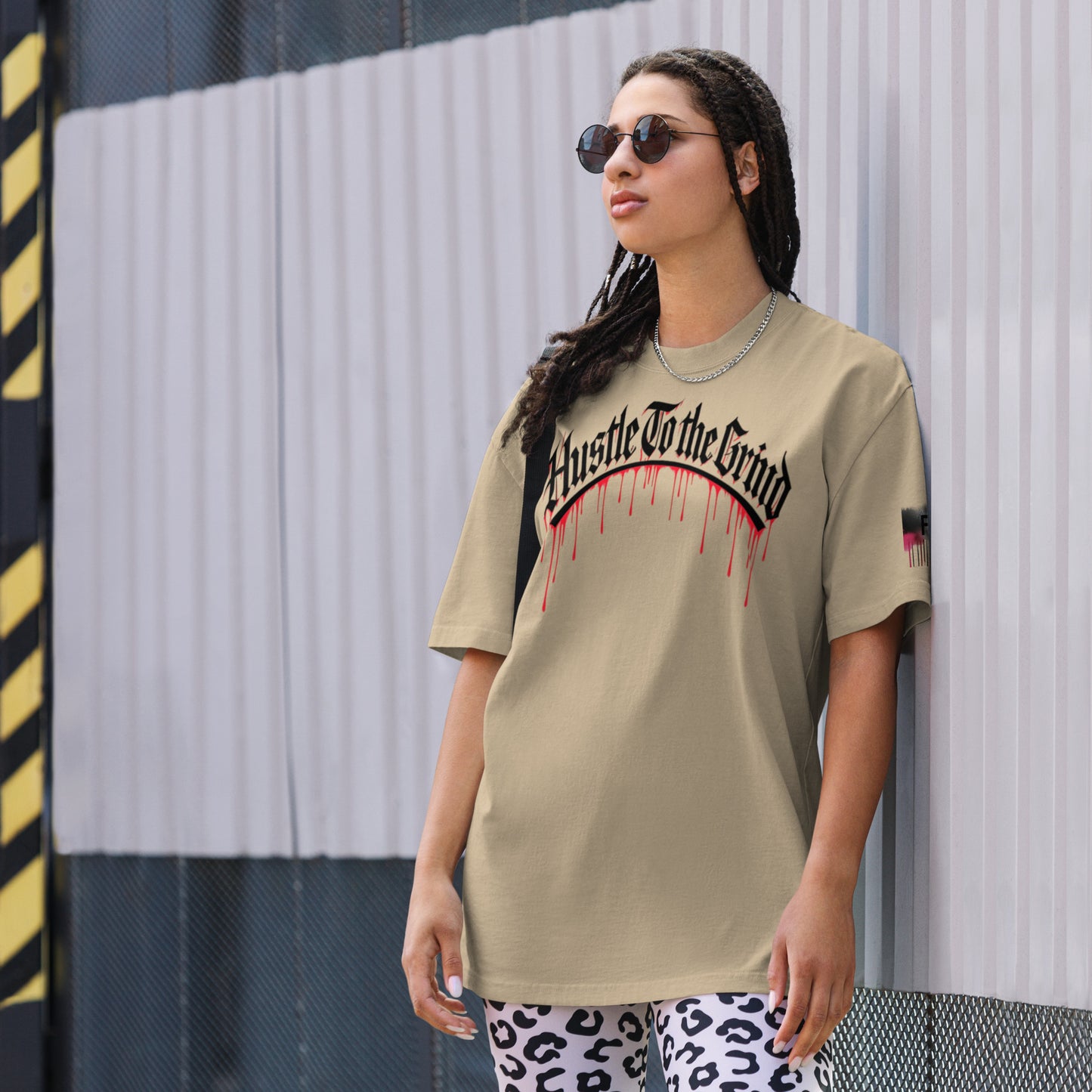 Oversized unisex T-shirt in faded bone color, featuring “Hustle to the Grind” streetwear graphic.