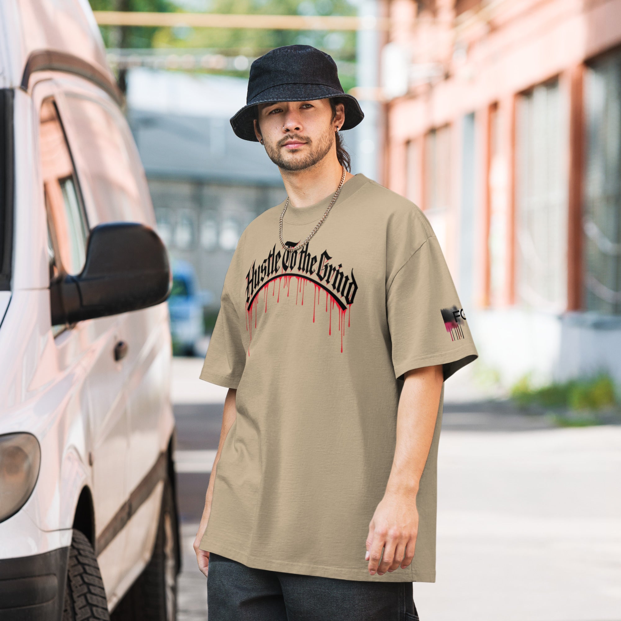 Oversized unisex T-shirt in faded bone color, featuring “Hustle to the Grind” streetwear graphic.